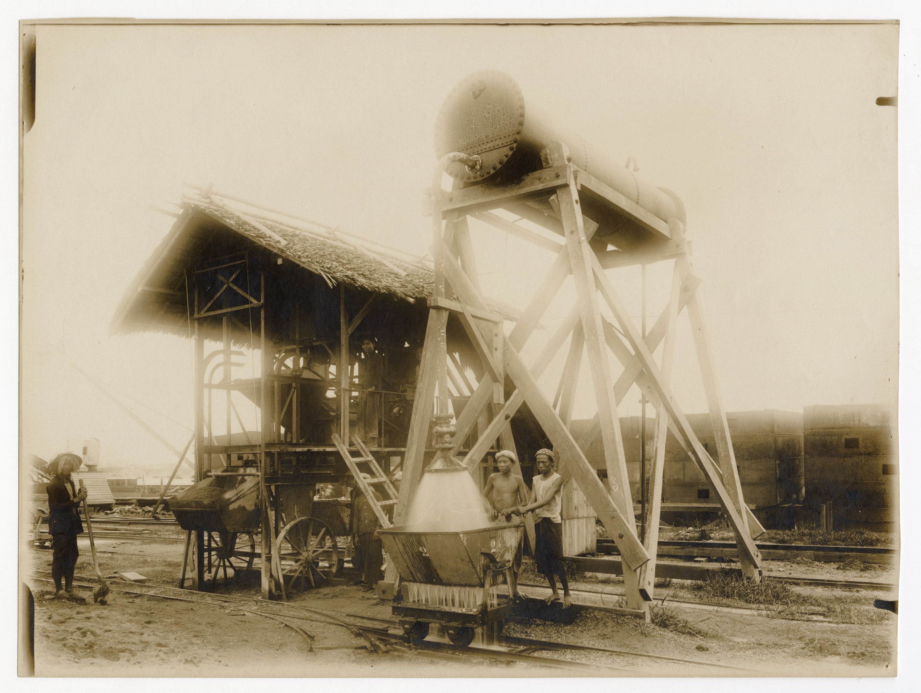 Photographie d'ouvriers indochinois et contremaîtres sur le chantier de construction d'un quai sur la rive droite de la rivière de Saigon, 1907-1910 : enlèvement des remblais et enrochements derrière le mur de quai.