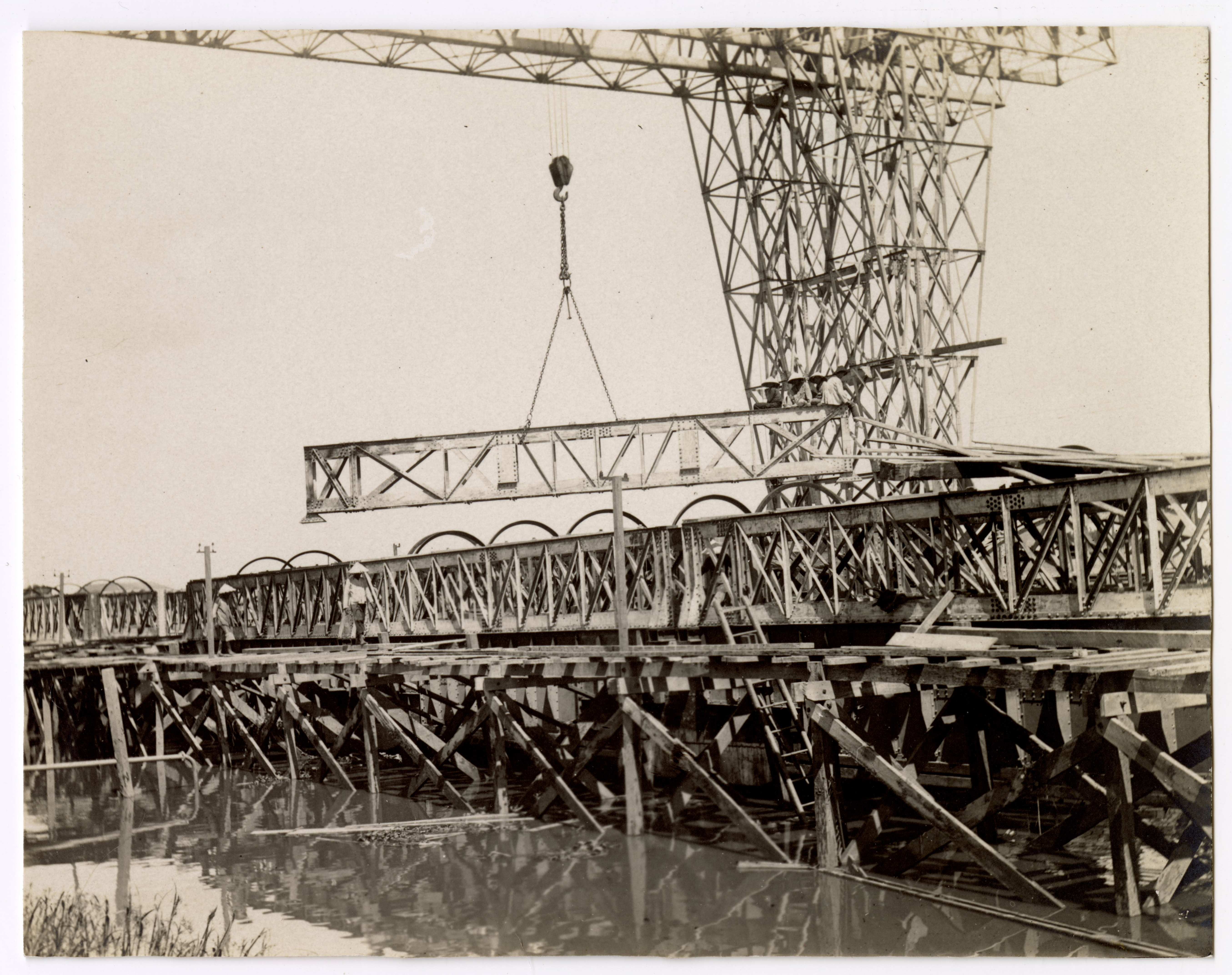 Photographie d'ouvriers indochinois et contremaîtres sur le chantier de construction d'un quai sur la rive droite de la rivière de Saigon, 1907-1910 : pont roulant.