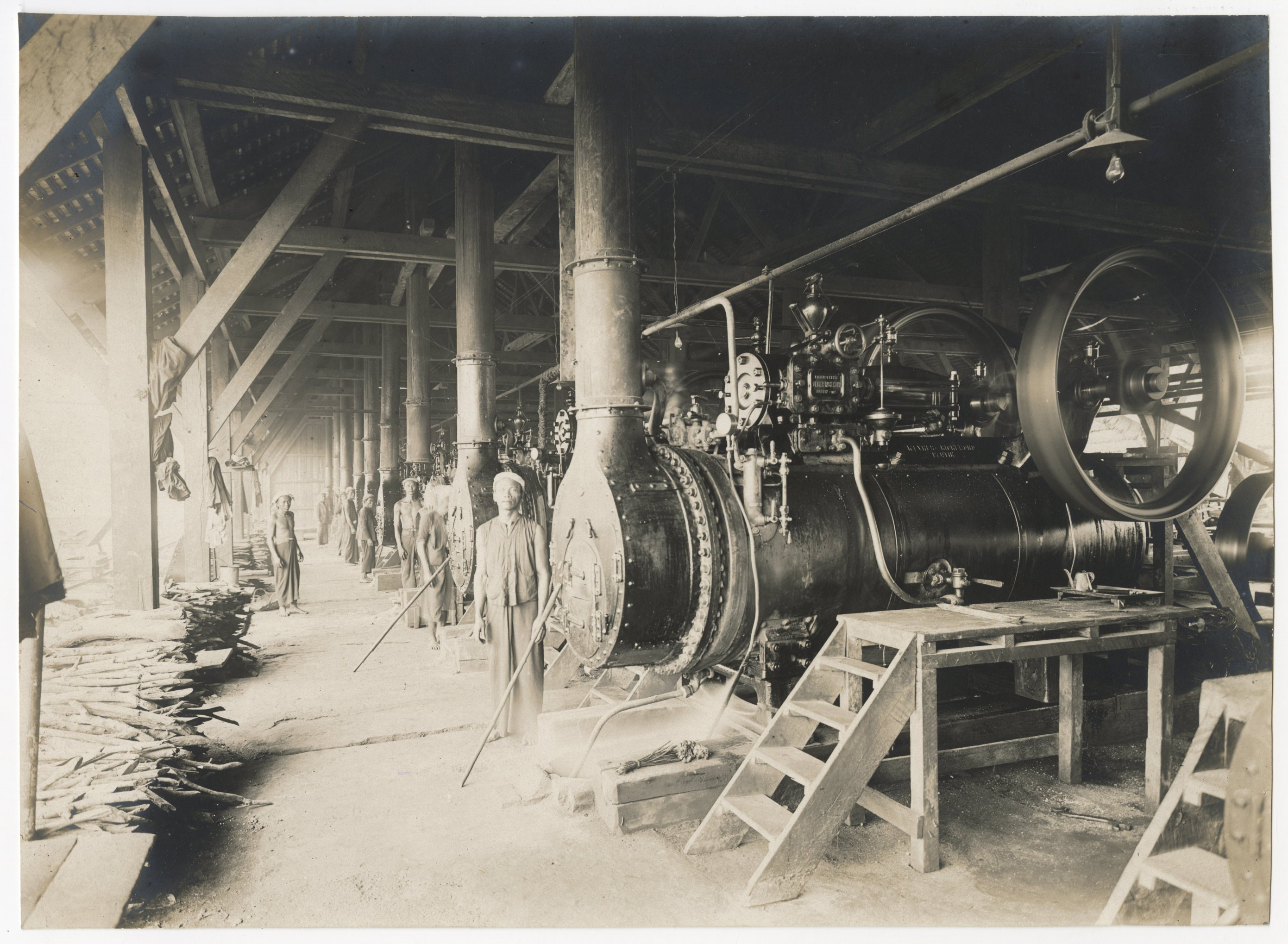 Photographie d'ouvriers indochinois et contremaîtres sur le chantier de construction d'un quai sur la rive droite de la rivière de Saigon, 1907-1910 : enlèvement des remblais et enrochements derrière le mur de quai.