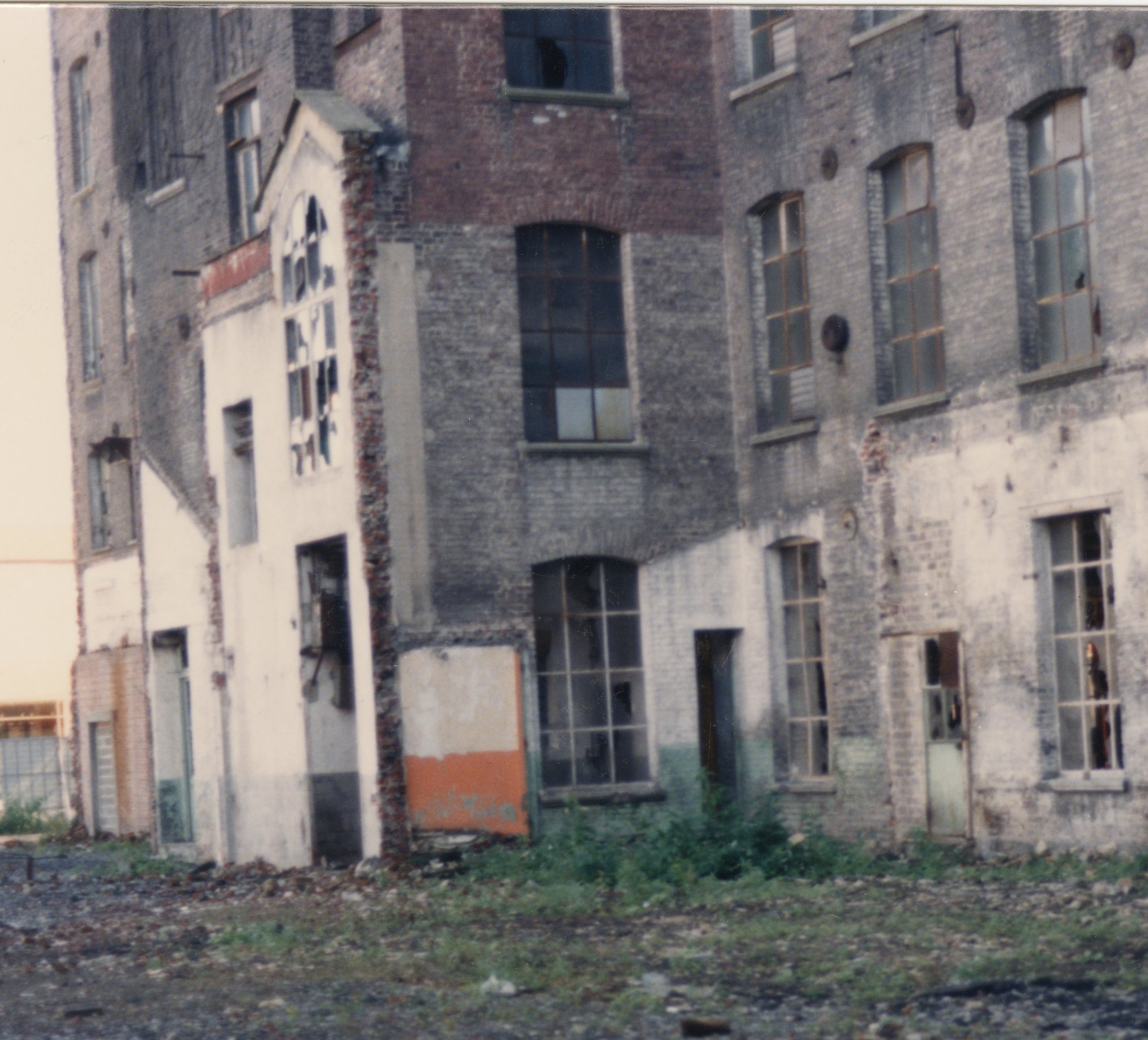 Photographie d'une façade de l'usine désaffectée, aux fenêtres cassées.