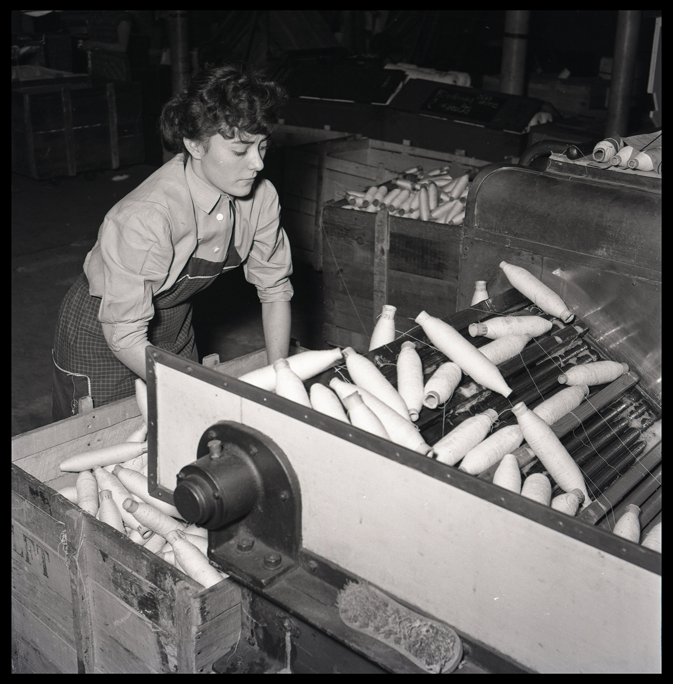 Ouvrière conditionnant des bobines de fils : tirage photographique, Lille (Nord), vers 1955.