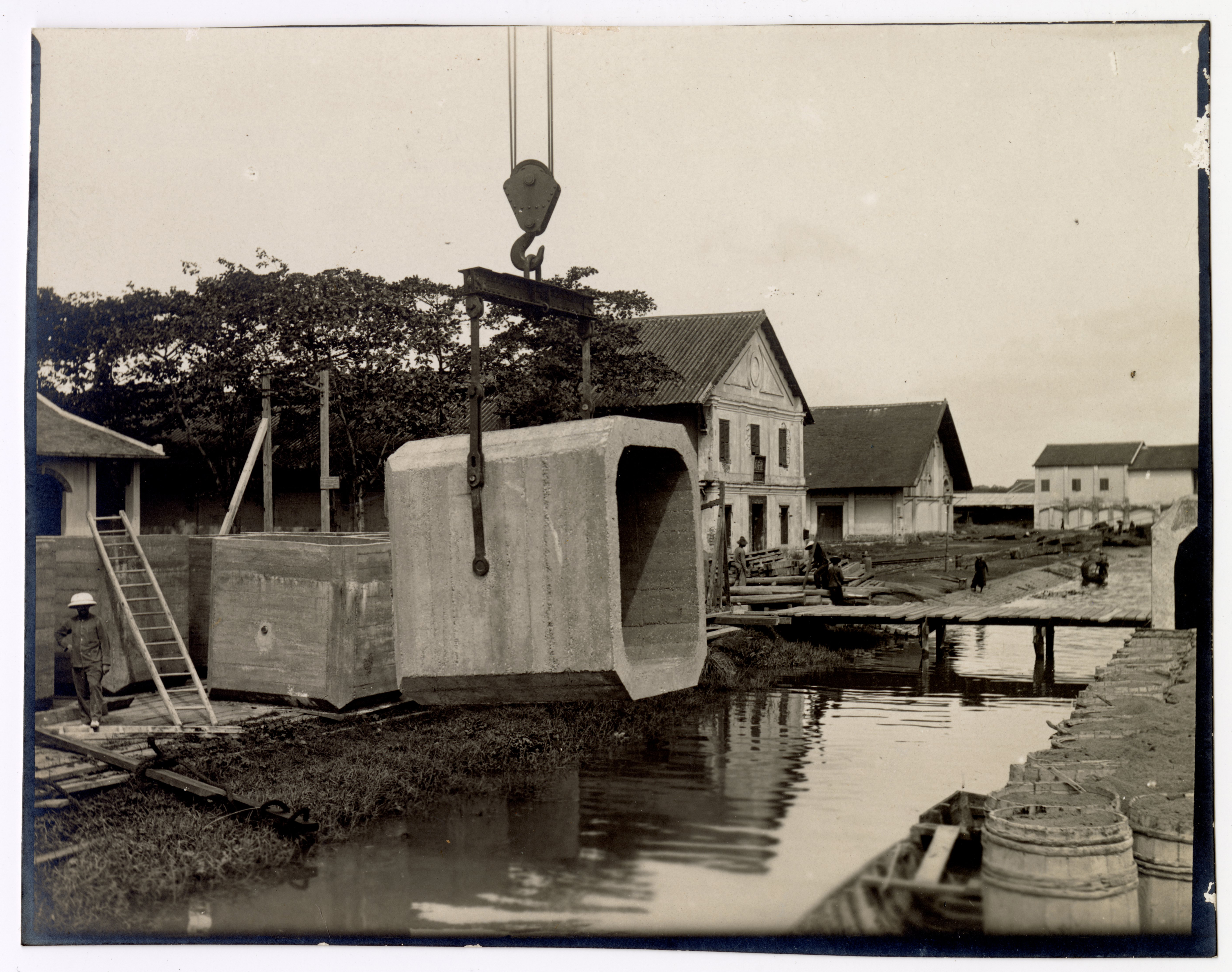 Photographie d'ouvriers indochinois et contremaîtres sur le chantier de construction d'un quai sur la rive droite de la rivière de Saigon, 1907-1910 : pont roulant.