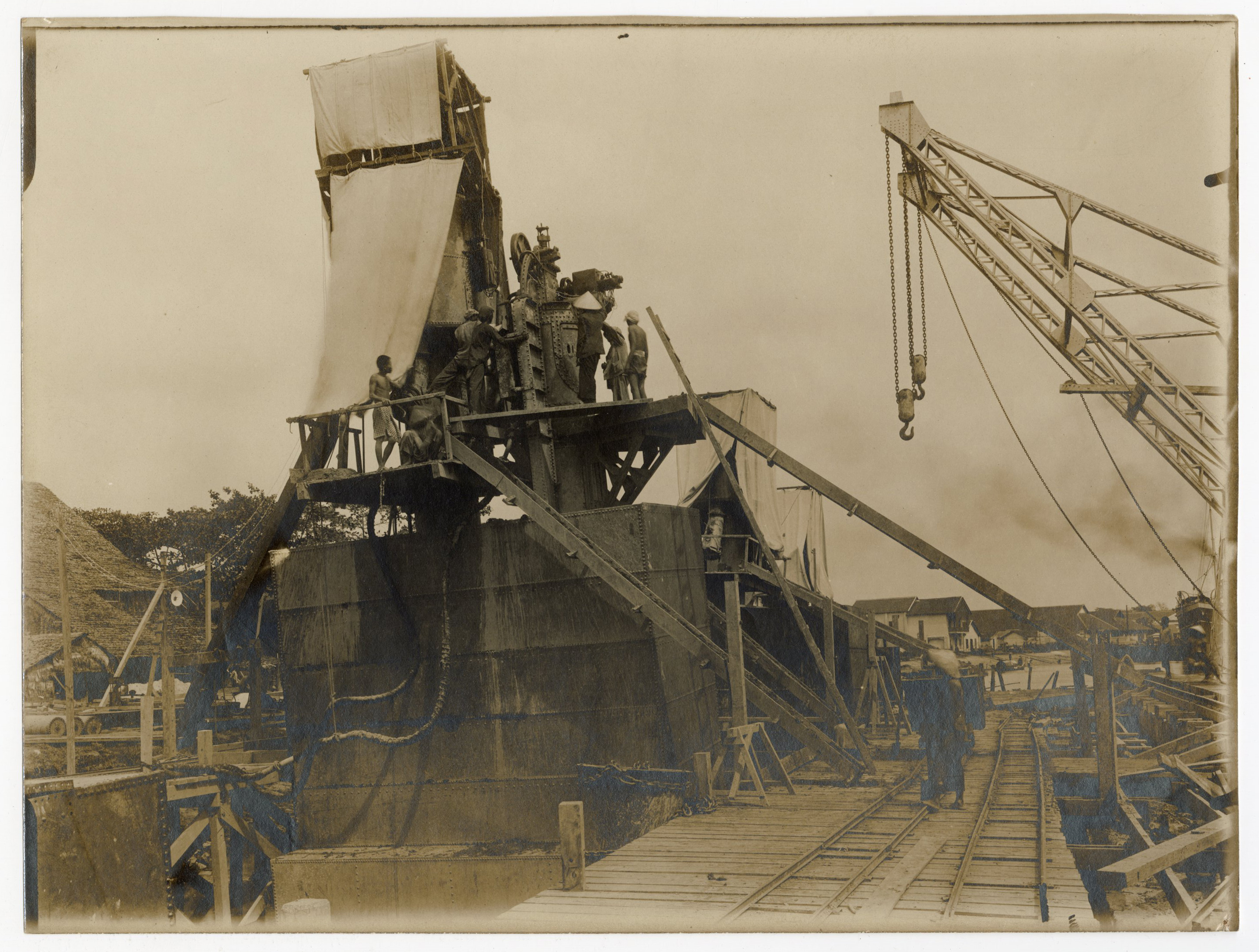 Photographie d'ouvriers indochinois et contremaîtres sur le chantier de construction d'un quai sur la rive droite de la rivière de Saigon, 1907-1910 : montage des caissons.