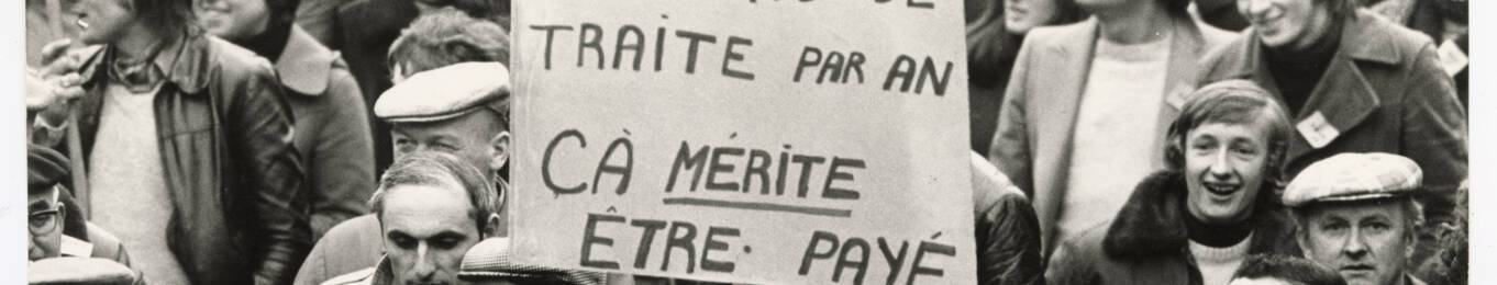 Agriculteurs brandissant une pancarte « 365 jours de traite par an, ça mérite être payé » lors d’une manifestation : photographie, sans lieu ni date.