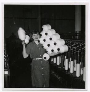 Une ouvrière textile pose avec ses bobines de fils, vers 1955.