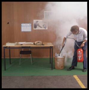Photographie d’un employé de Phildar apprenant à manipuler un extincteur, 1983-1984.