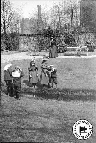 Moment de jeux dans un parc situé à l’emplacement de la première filature de coton Motte-Bossut (dite l’Usine monstre). En arrière-plan, on devine la silhouette de la nouvelle filature qui deviendra les Archives nationales du monde du travail.  Roubaix, début du XXe siècle.